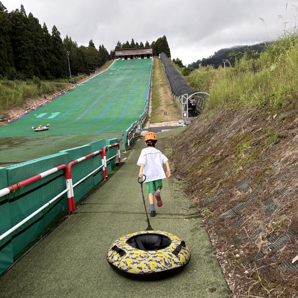 ロッテアライリゾートのチュービング浮き輪を引いて坂を駆け上がる7歳長男