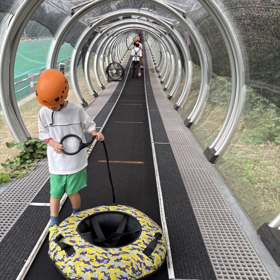 ロッテアライリゾートのチュービング浮き輪を引いて動く歩道に乗っている7歳長男